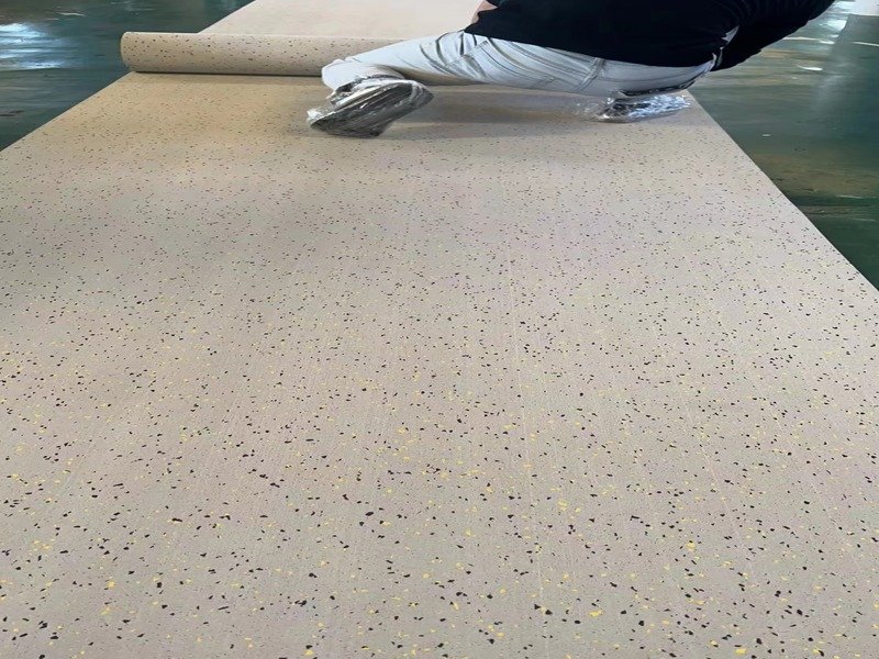 Un installateur professionnel utilisant un rouleau lourd de 50 kg sur un revêtement de sol en rouleau en caoutchouc fraîchement posé.